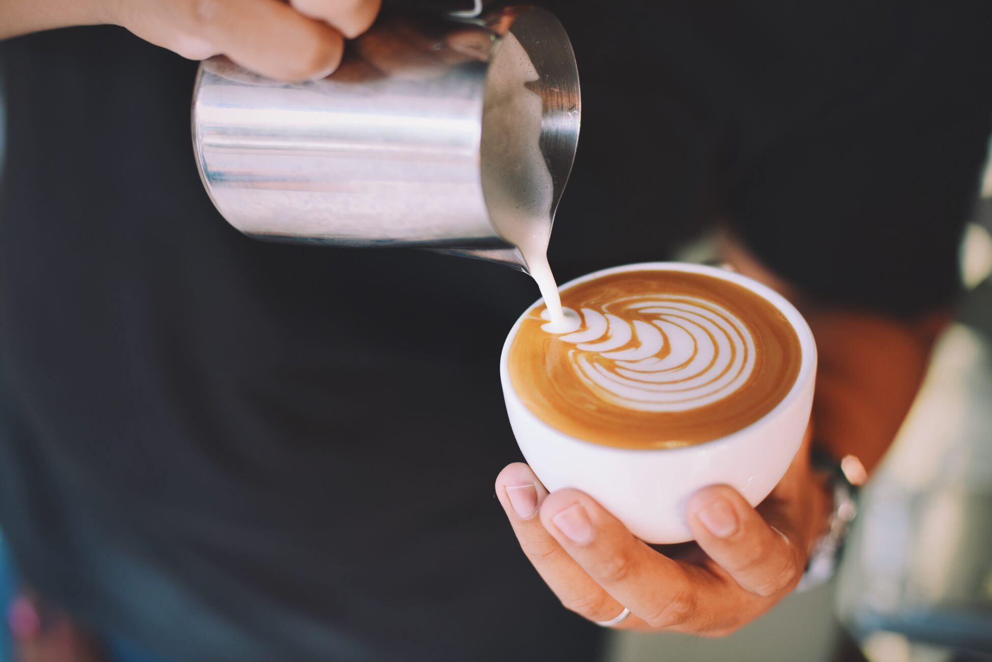 Barista pouring tulip latte art into cup Barista pouring tulip latte art into cup