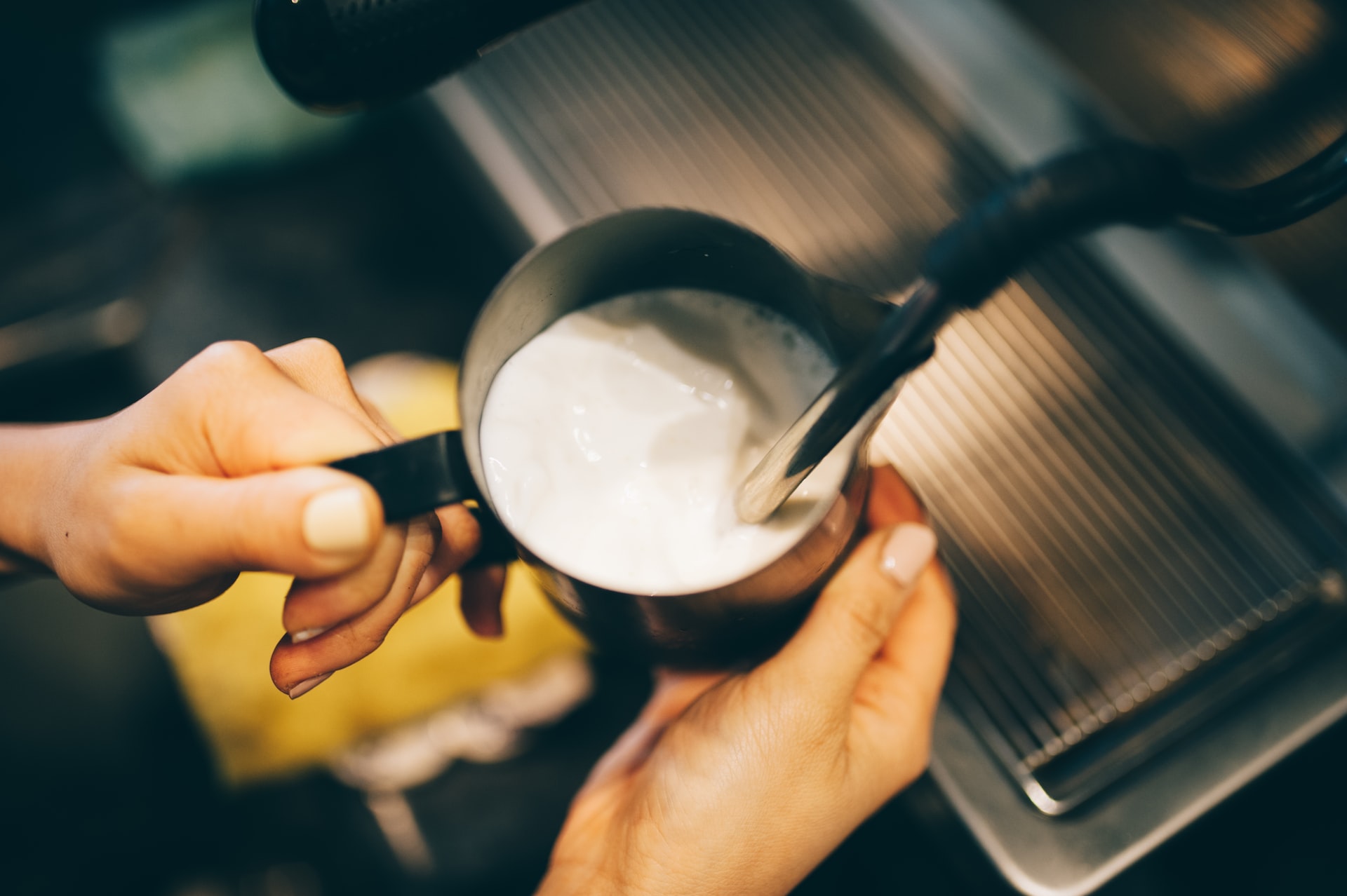 barista frothing milk with steam wand at a cafe